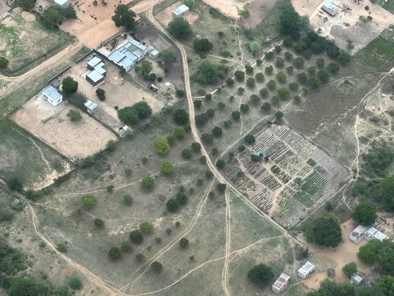 Aerial view of the middle catchment — homesteads, orchards, and cleared ground where people and landscape intersect.