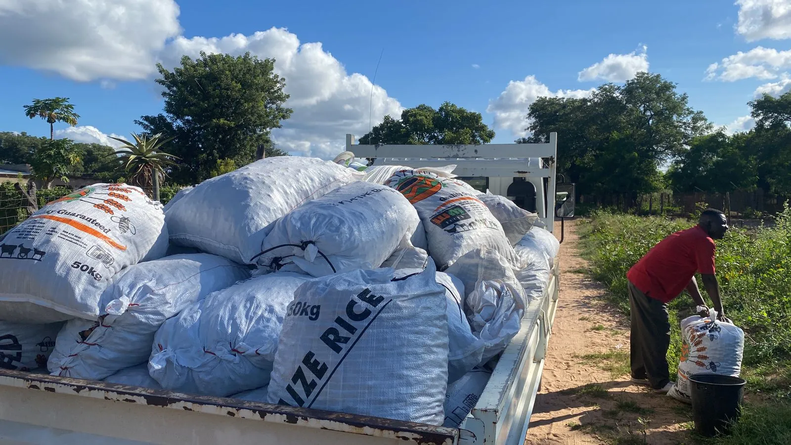 A flatbed truck loaded with hand-labelled custodian kernel sacks — each bag tied to a named household