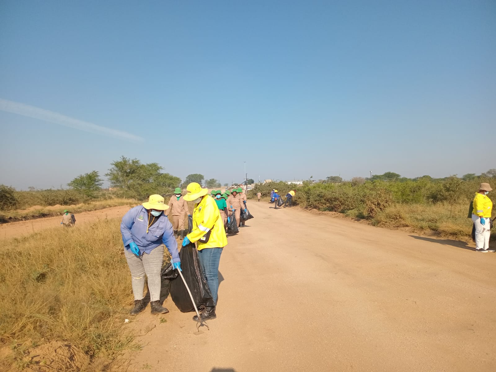 A line of workers strung along the dirt road, clearing the verge between Justicia and Lillydale.