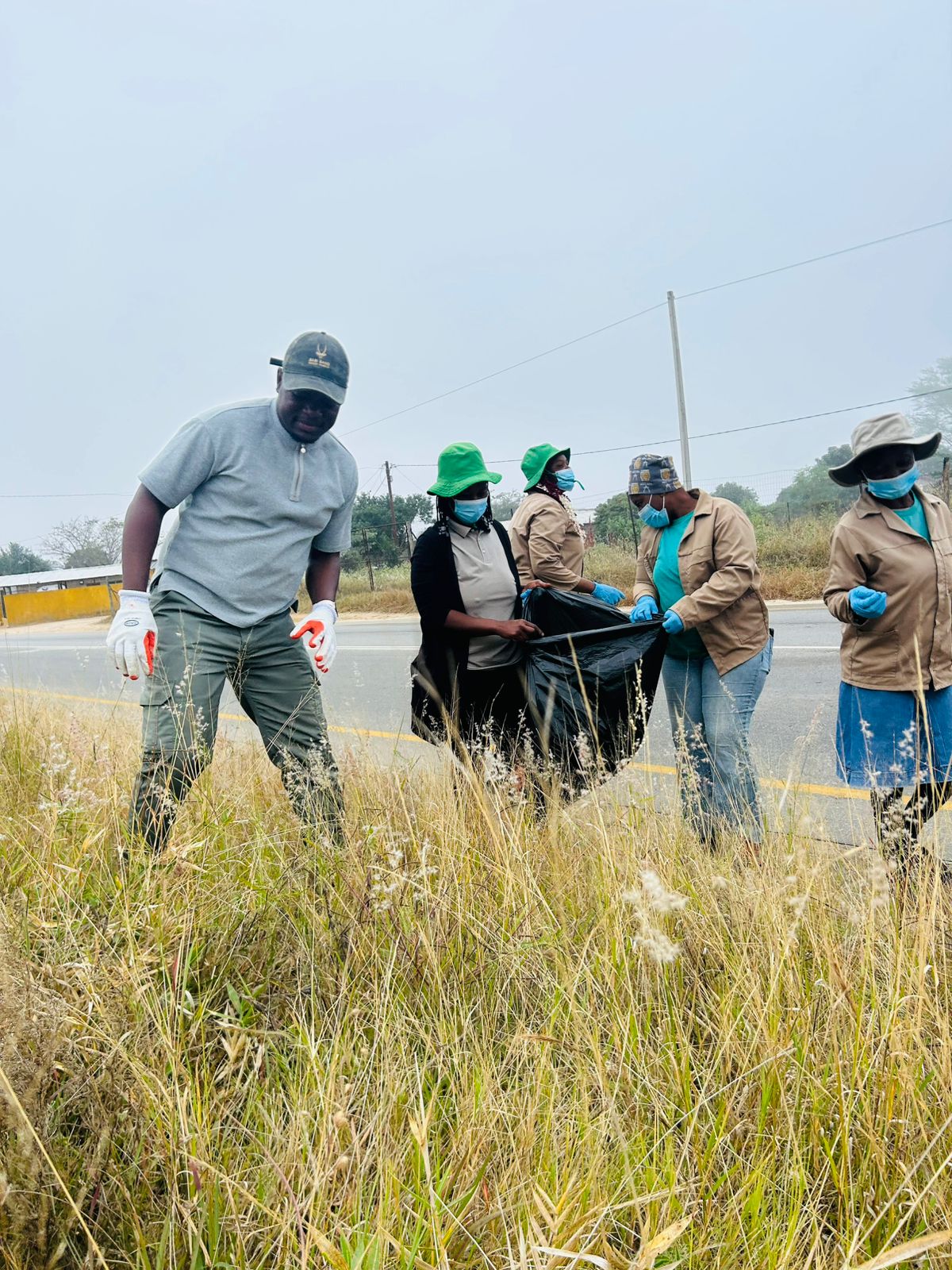Volunteers bent to the roadside verge, filling a bag with litter cleared from the grass.